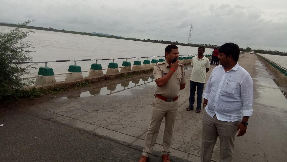 Tahsildar Manjunath and Sub-inspector L B Agni inspect the Huvinahedgi bridge across the swollen Krishna river in Devadurga taluk, Raichur district, on Friday.