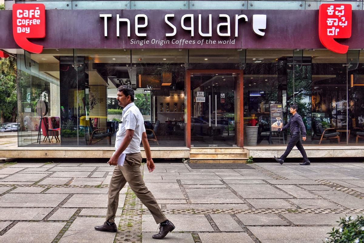 People walk past a closed outlet of Cafe Coffee Day retail chain belonging to coffee baron and founder V.G. Siddhartha in Bangalore on July 31, 2019. - The body of billionaire Indian coffee magnate V.G. Siddhartha was found by a river in southern India on