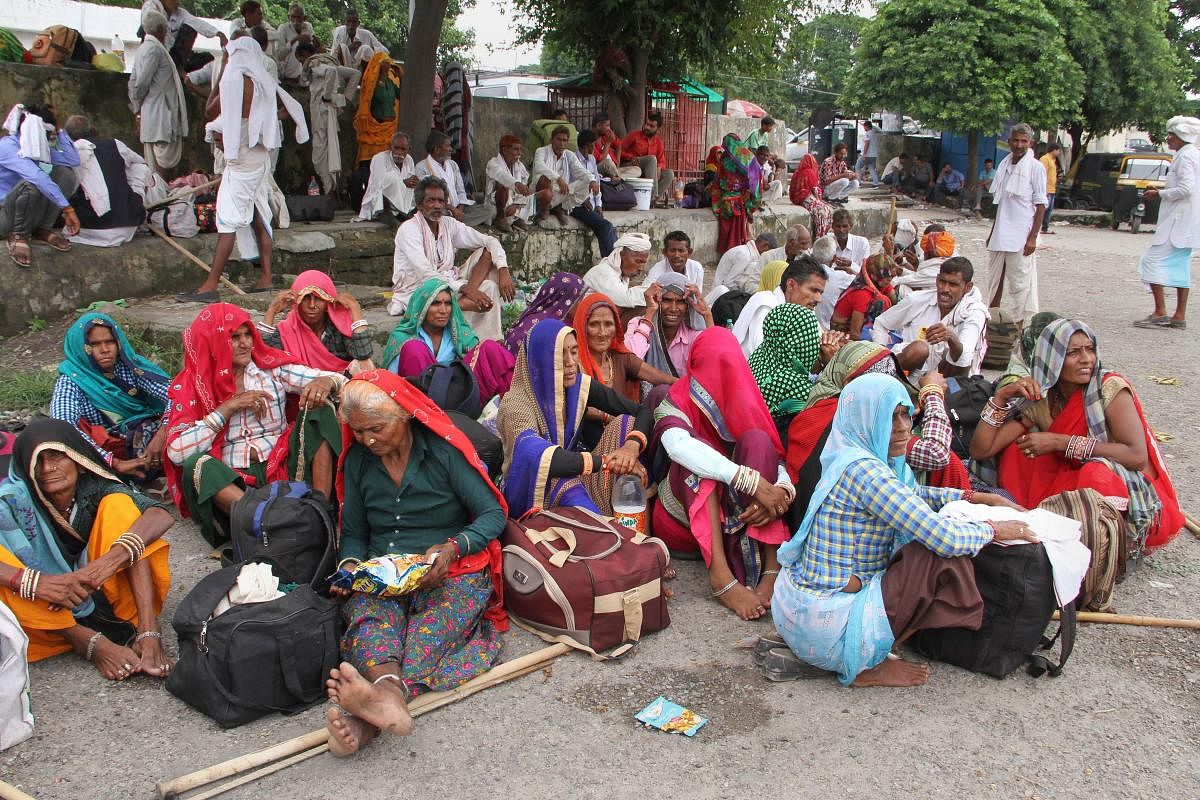 Tourists and passengers sit on the road as they prepare to leave at Jammu Railway Station in Jammu (PTI Photo)