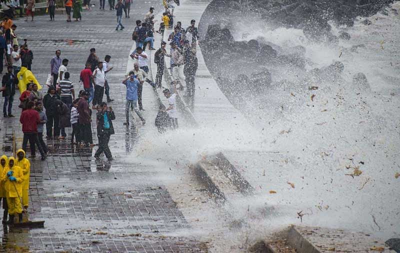 Brihanmumbai Municipal Corporation (BMC) workers clear the garbage washed ashore during high tide, on the promenade along the Marine Drive, in Mumbai. (PTI Photo)