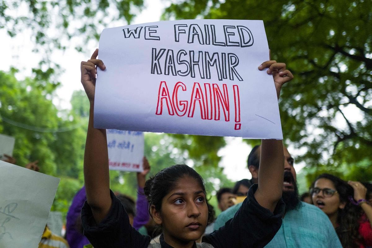 An activist and supporter of Indian left wing parties holds a placard during a demonstration to protest against the presidential decree abolishing Article 370 of the constitution giving special autonomy to Muslim-majority Kashmir, in New Delhi on August 5, 2019. - The Indian government on August 5 rushed through a presidential decree to scrap a special status for disputed Kashmir, hours after imposing a major security clampdown in the region. (AFP)