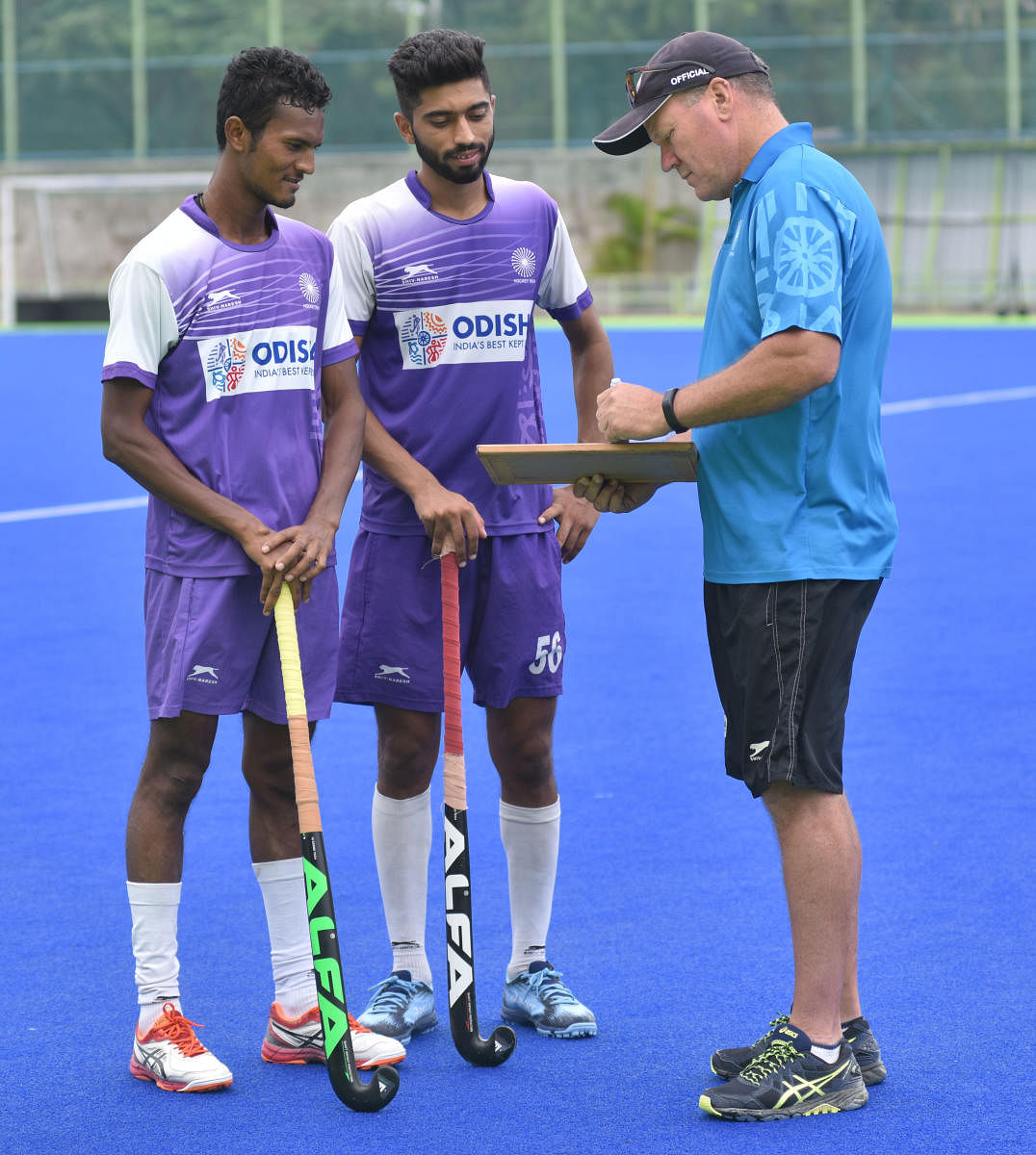 (From left) Ashis Topno and Shamsher Singh are all ears as chief coach Graham Reid discusses a point during a training session on Tuesday. DH PHOTO/ JANARDHAN BK