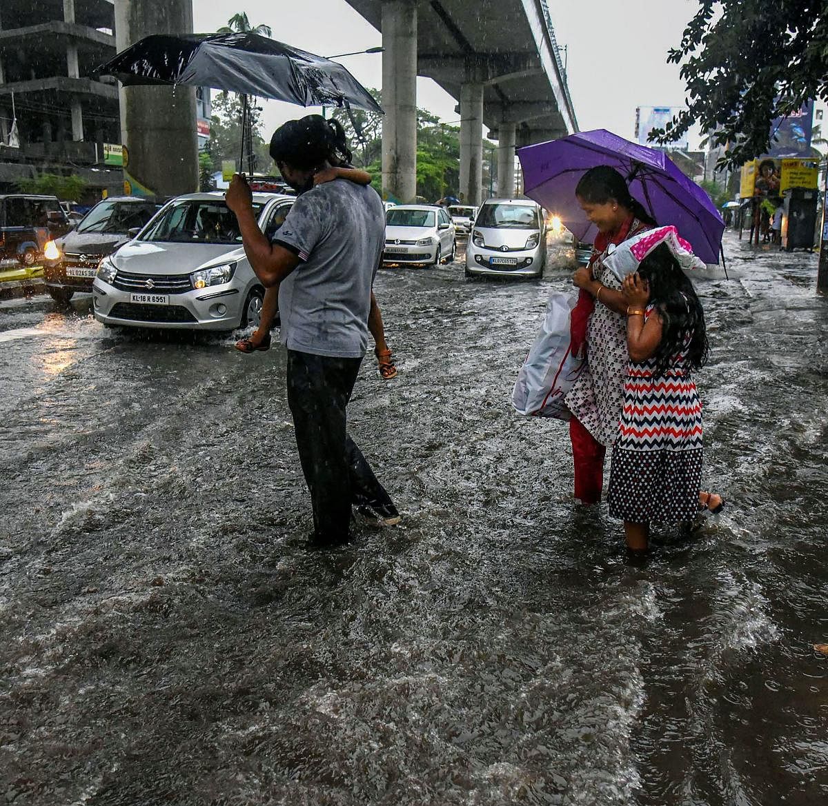 A family crosses a flooded road during Monsoon rains in Kochi (PTI Photo)