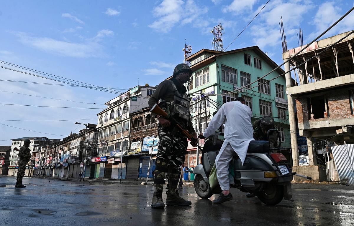 An Indian security personnel stops a motorist to check during a curfew in Srinagar. AFP photo