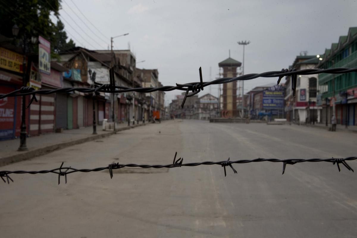 Srinagar: In this Tuesday, Aug. 6, 2019 photo, a deserted street is seen through a barbwire set up as blockade during curfew in Srinagar. AP-PTI