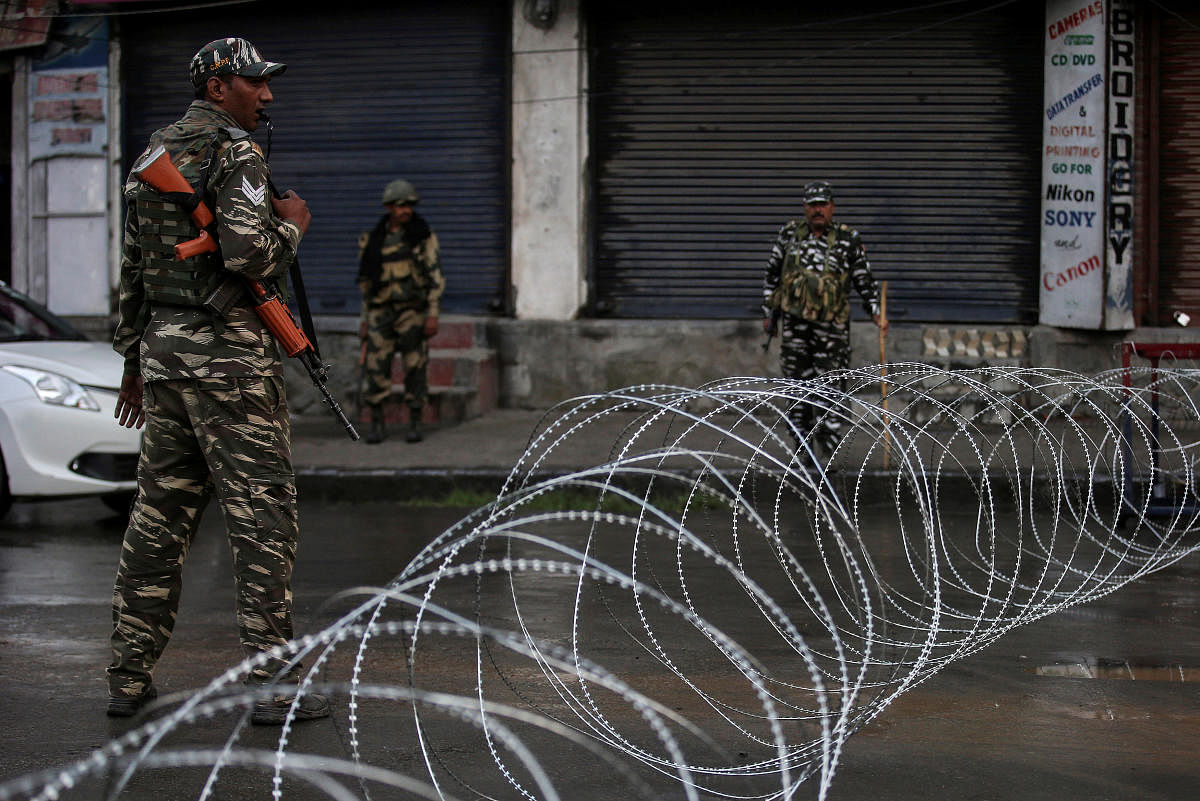 Security forces personnel stand guard next to concertina wire laid across a road during restrictions after the government scrapped special status for Kashmir, in Srinagar on August 7, 2019. REUTERS