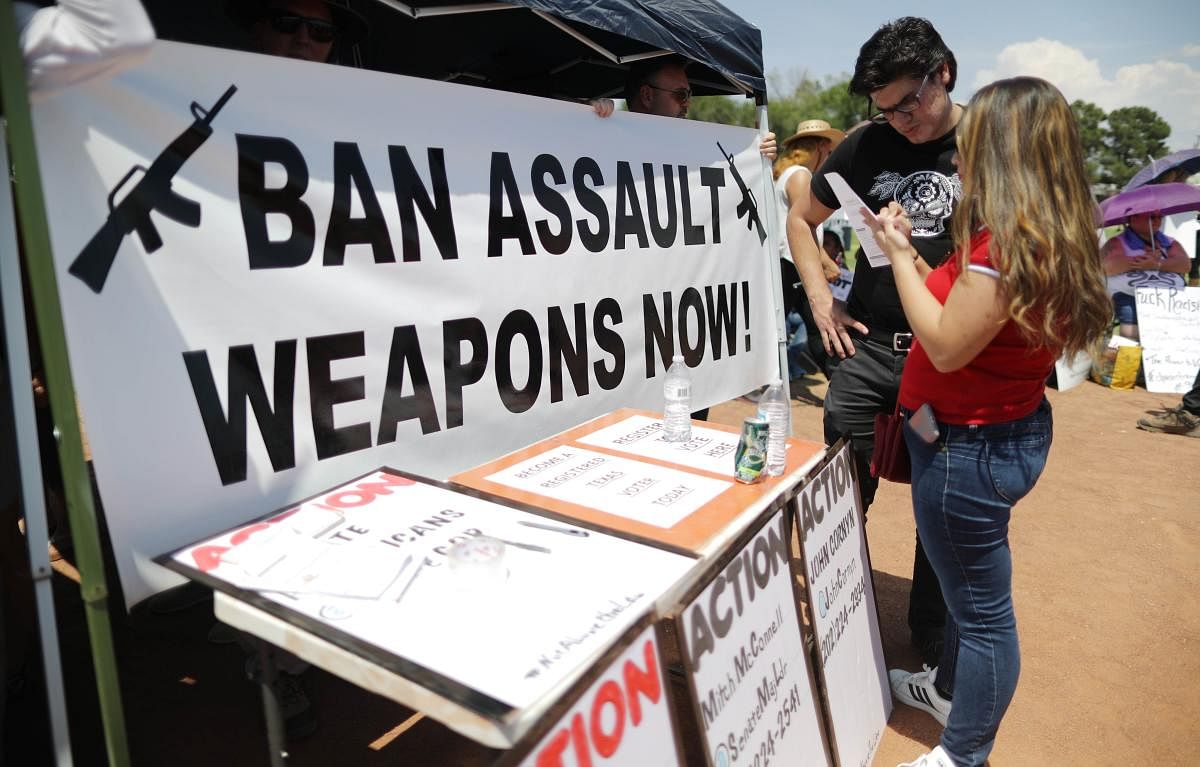A 'Ban Assault Weapons Now' sign is displayed near a voter registration table at a protest against President Trump's visit, following a mass shooting which left at least 22 people dead. AFP Photo