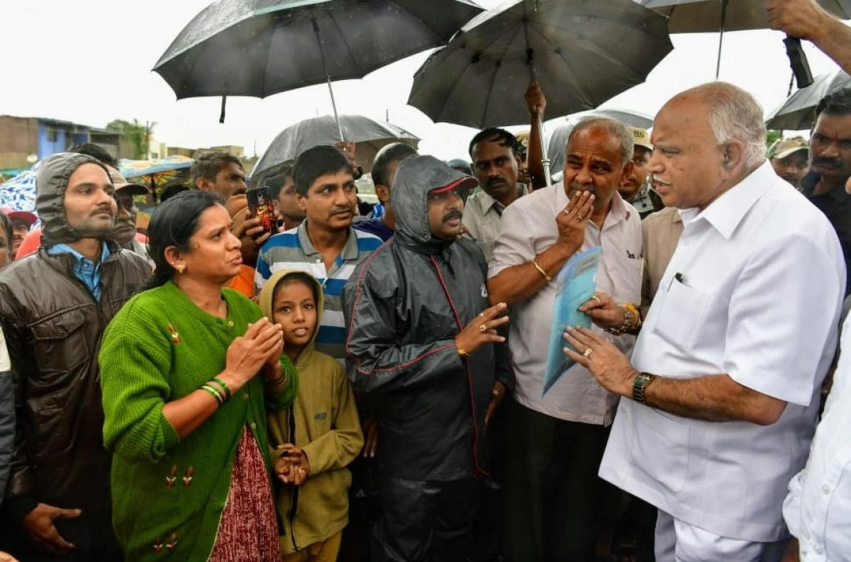 Chief Minister B S Yediyurappa interacts with flood-affected people in Sankeshwar town of Belagavi district on Thursday. DH Photo