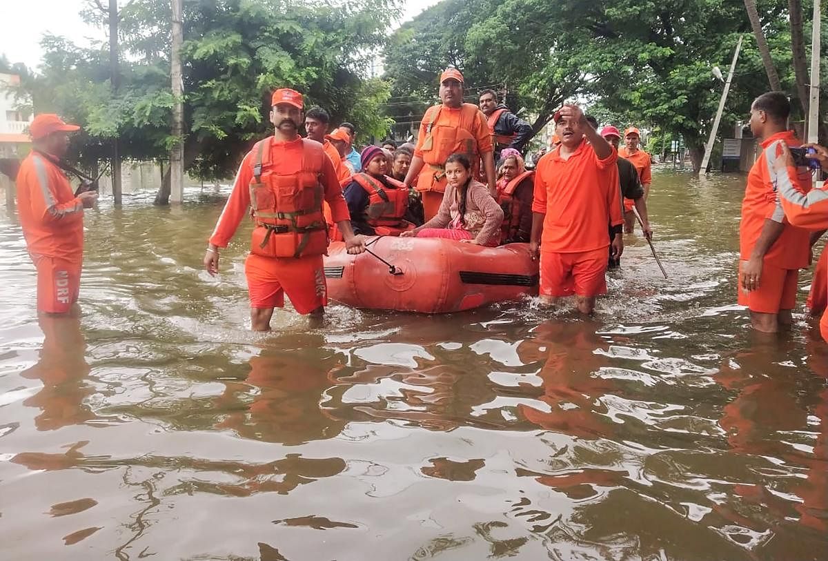NDRF personnel rescue people stranded in flood waters on inflatable boats after heavy rains on the outskirts of Sangli in Maharashtra state. AFP photo