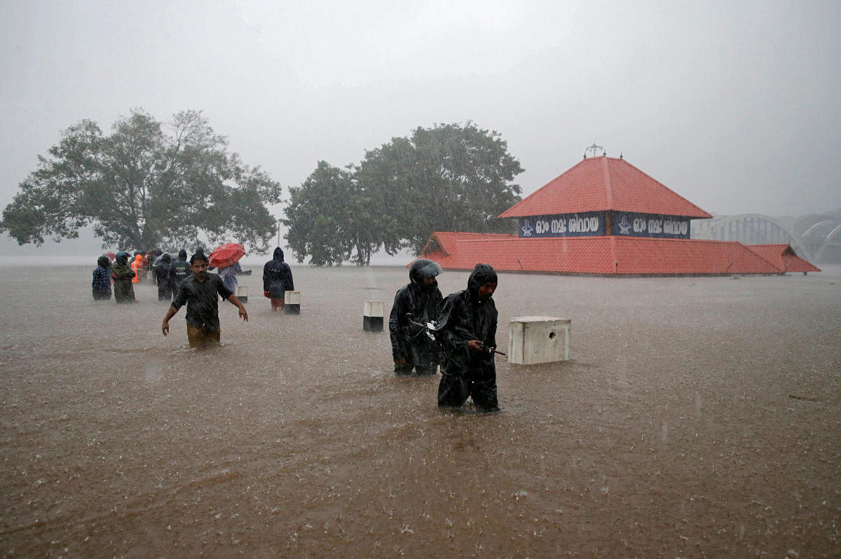 Members of a rescue team wade through a water-logged area past a submerged temple during heavy rains on the outskirts of Kochi. Reuters. 