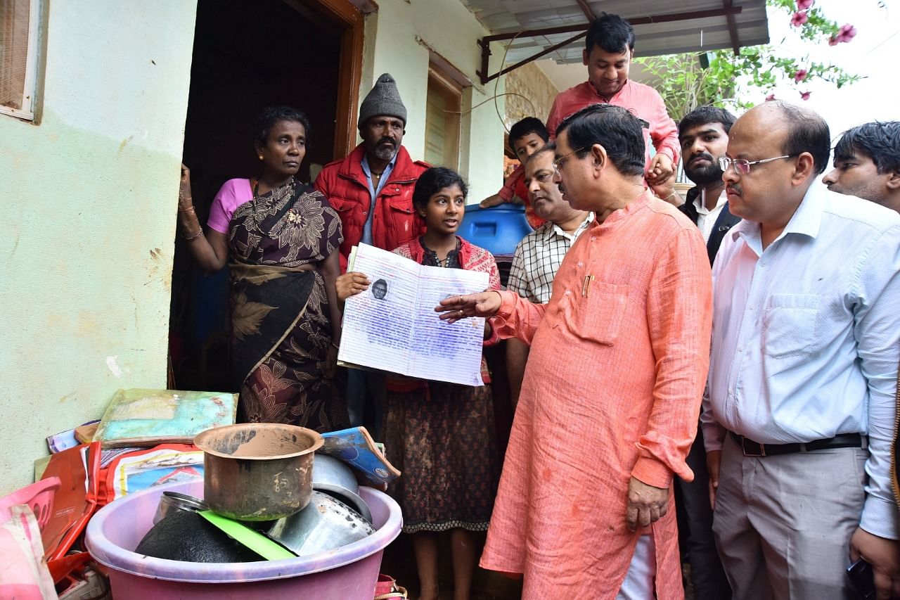 Pralhad Joshi interacts with a student whose books were damaged due to heavy rains in Hubballi. He assured of providing free books to all the students who lost their books in rain related incidents. DH photo