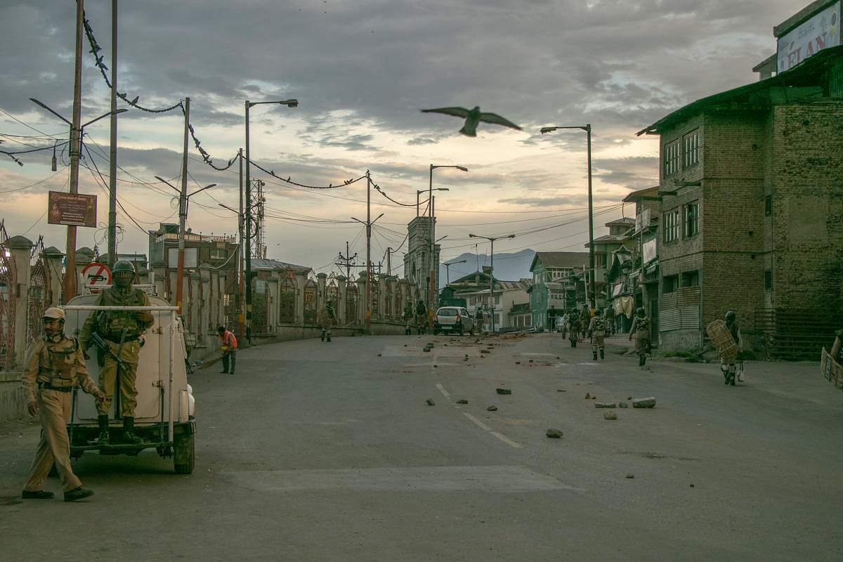 Security personnel walk on a street in Srinagar as widespread restrictions on movement and a telecommunications blackout remained in place. (AFP Photo)