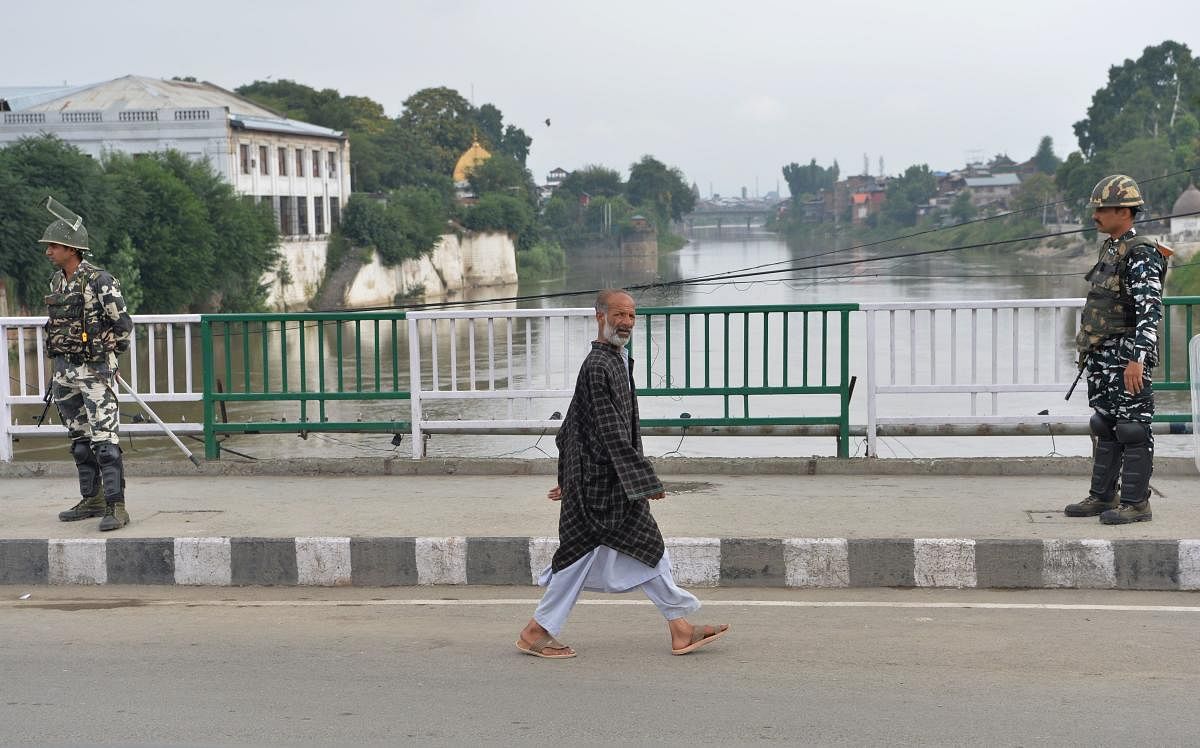 A man walks past security personnel guarding a street during a lockdown in Srinagar on August 11, 2019, after the Indian government stripped Jammu and Kashmir of its autonomy. AFP photo