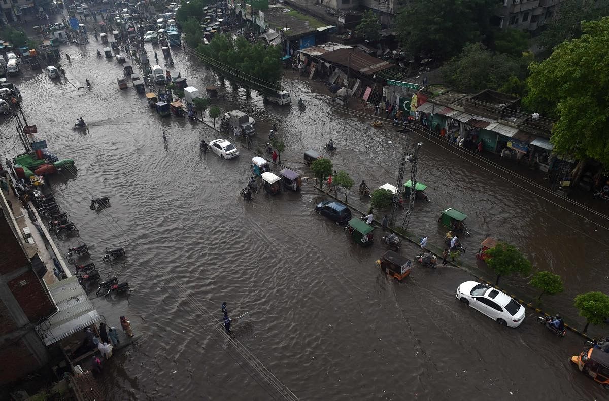 Commuters make their way on a flooded street after heavy monsoon rains in Lahore on August 1, 2019. (Photo by ARIF ALI / AFP)