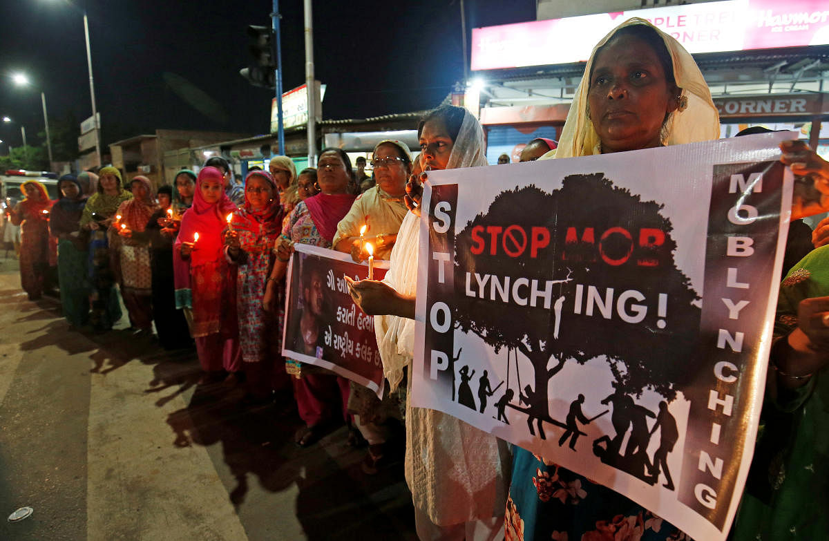 Women hold placards and candles during a protest against recent mob lynchings across the country, in Ahmedabad. REUTERS/ File photo
