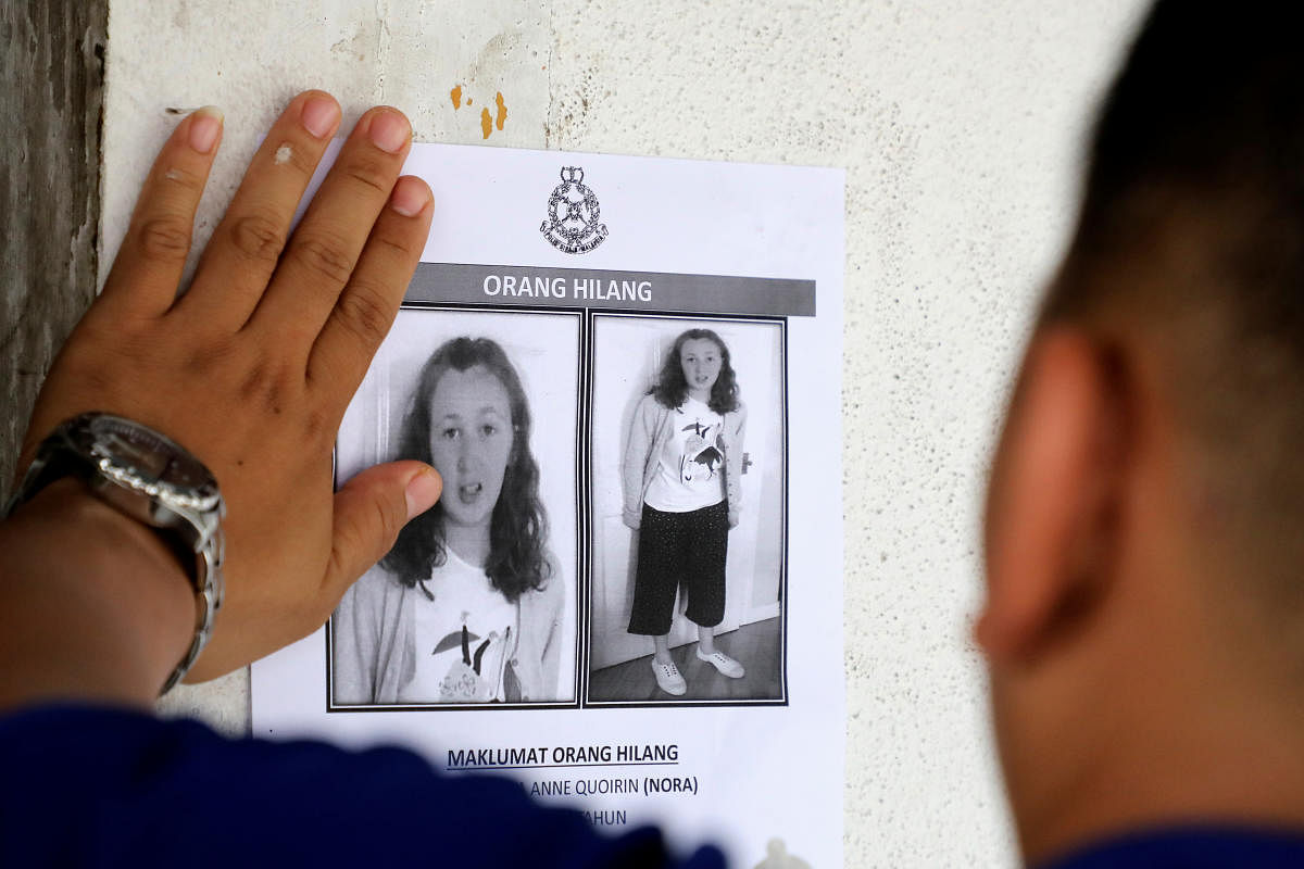 A police officer paste a photo of 15-year-old Irish girl Nora Anne Quoirin who went missing from a resort on a wall at a shop in Seremban, Malaysia. (Reuters Photo)
