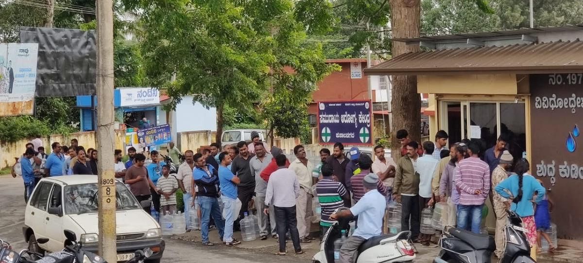 People queue up in front of the clean drinking water unit near the community health centre in Kushalnagar town.