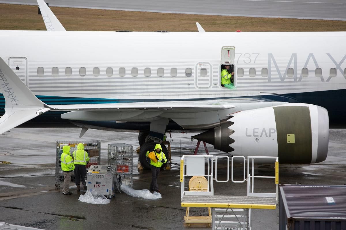 (FILES) In this file photo taken on March 12, 2019 workers are pictured next to a Boeing 737 MAX 9 airplane on the tarmac at the Boeing Renton Factory in Renton, Washington. - Boeing acknowledged on May 18, 2019 that it had to correct defects in its fligh
