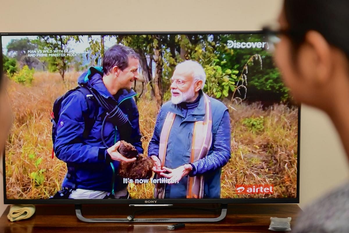 People watch on television the special edition of 'Man Vs Wild' series hosted by survival expert Bear Grylls (R), going on a mission with Indian Prime Minister Narendra Modi, in Bangalore on August 12, 2019. (AFP)