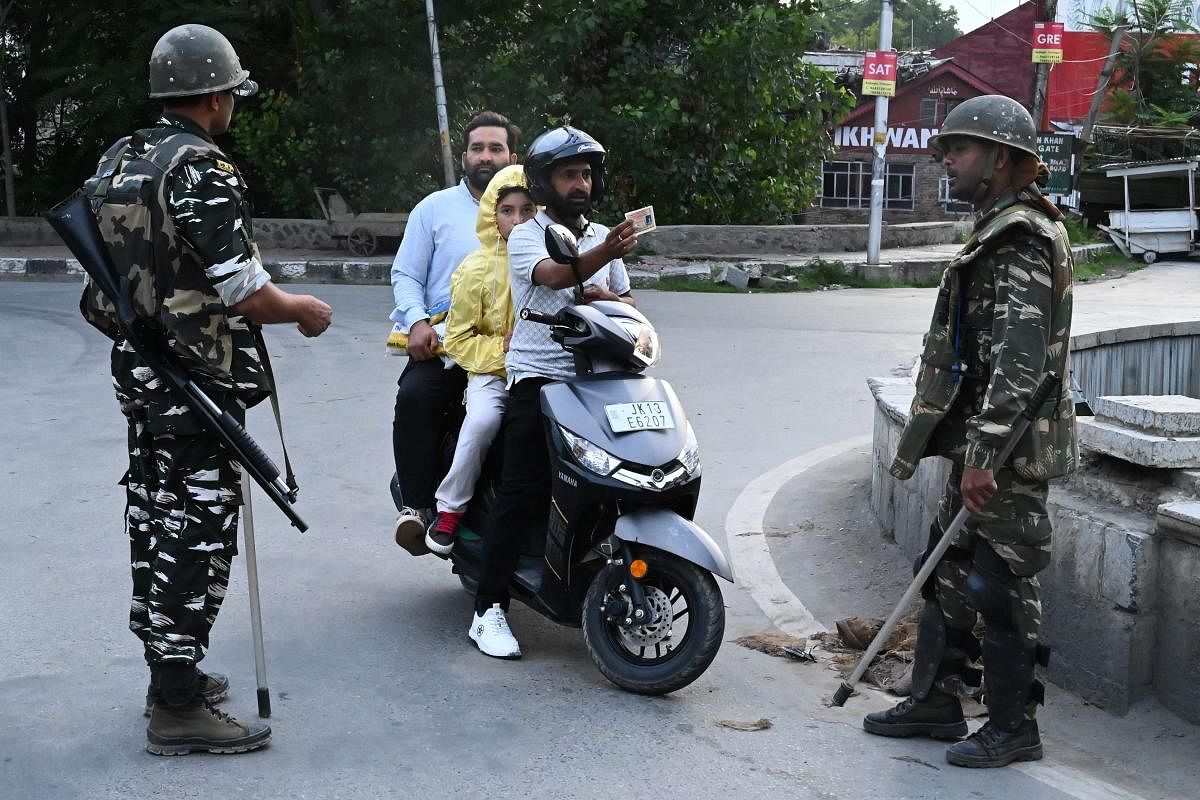 A motorist shows his identity card to a security personnel after being stopped for questioning at a roadblock during a lockdown in Srinagar. AFP photo.