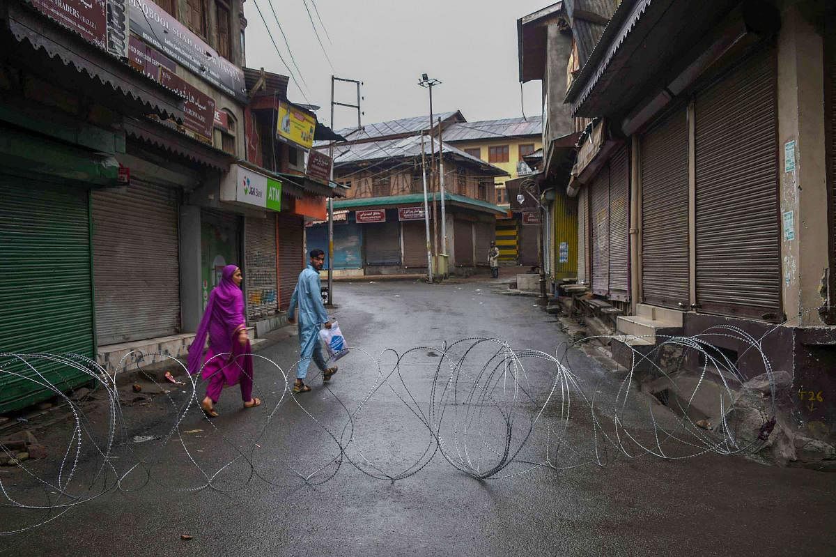 A man and a woman walk in a street during curfew like restrictions following abrogation of the provisions of Article 370, in Srinagar. PTI photo