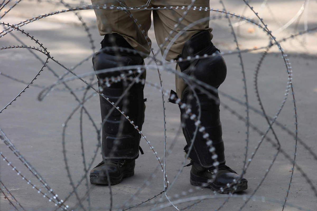 An Indian police officer stands behind the concertina wire during restrictions on Eid-al-Adha after the scrapping of the special constitutional status for Kashmir by the Indian government, in Srinagar, August 12, 2019. REUTERS/Danish Ismail