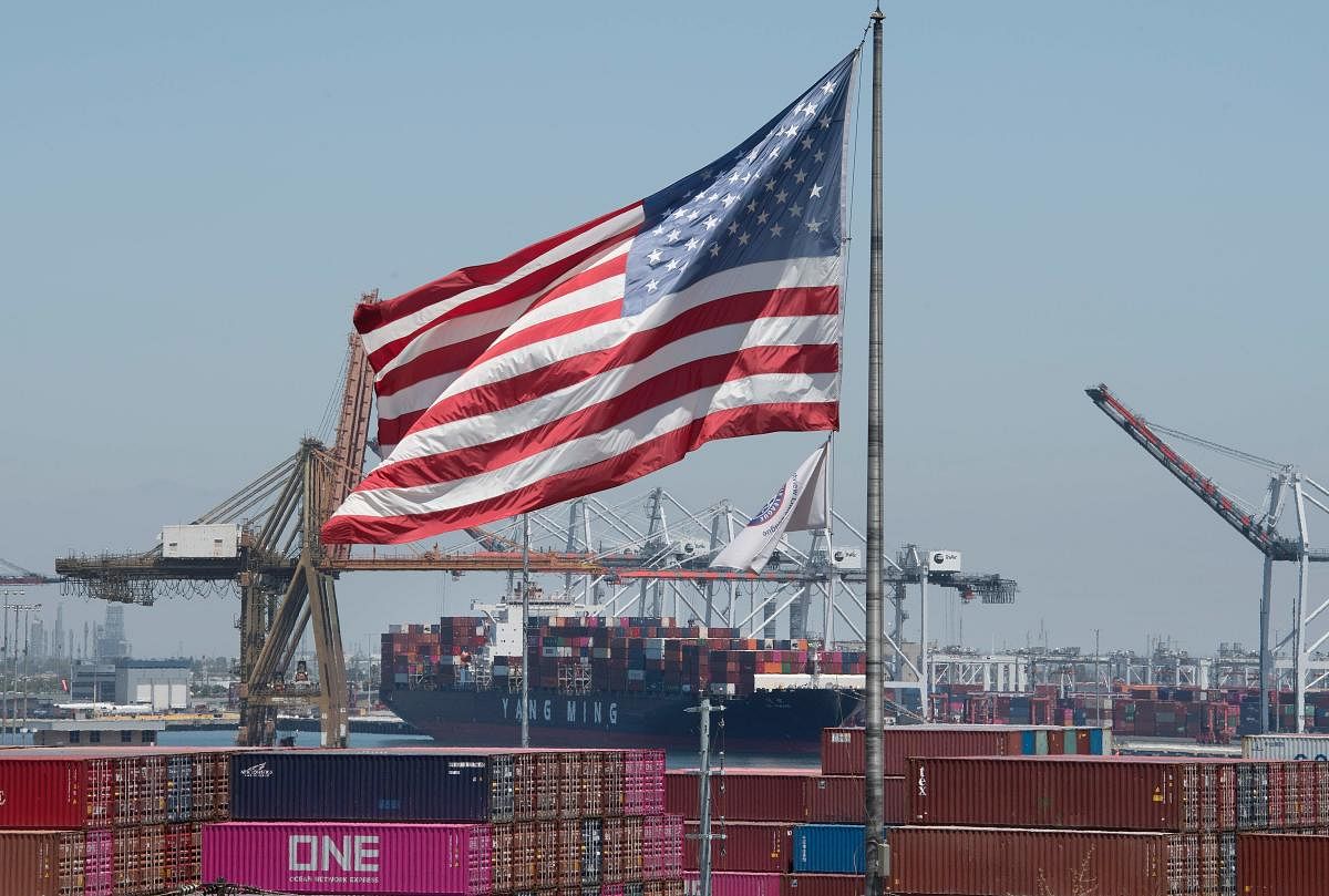 The US flag flies over a container ship unloading it's cargo from Asia, at the Port of Long Beach, California on August 1, 2019. - President Donald Trump announced August 1 that he will hit China with punitive tariffs on another $300 billion in goods, esc