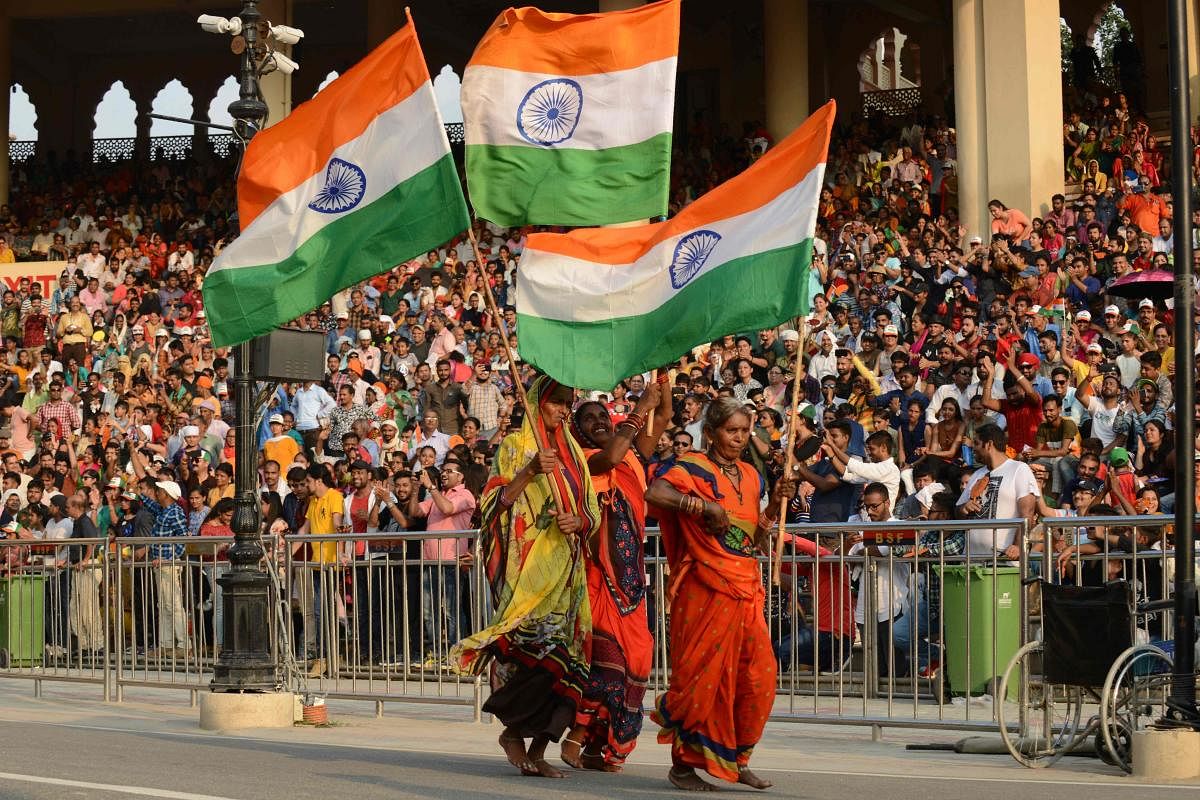Indian women carry Indian flags during the Beating Retreat ceremony at the India Pakistan Wagah border post some 35 kms from Amritsar on August 10, 2019. (Photo by NARINDER NANU / AFP)