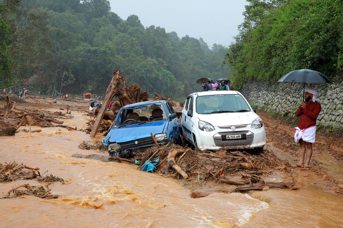 A man stands next to damaged cars after a landslide caused by torrential monsoon rains at Puthumala near Meppadi, Wayanad district, Kerala. Reuters photo