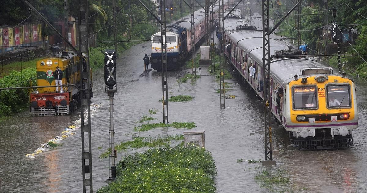 Suburban trains chug on water-logged tracks during heavy rains, in Mumbai. (PTI Photo)