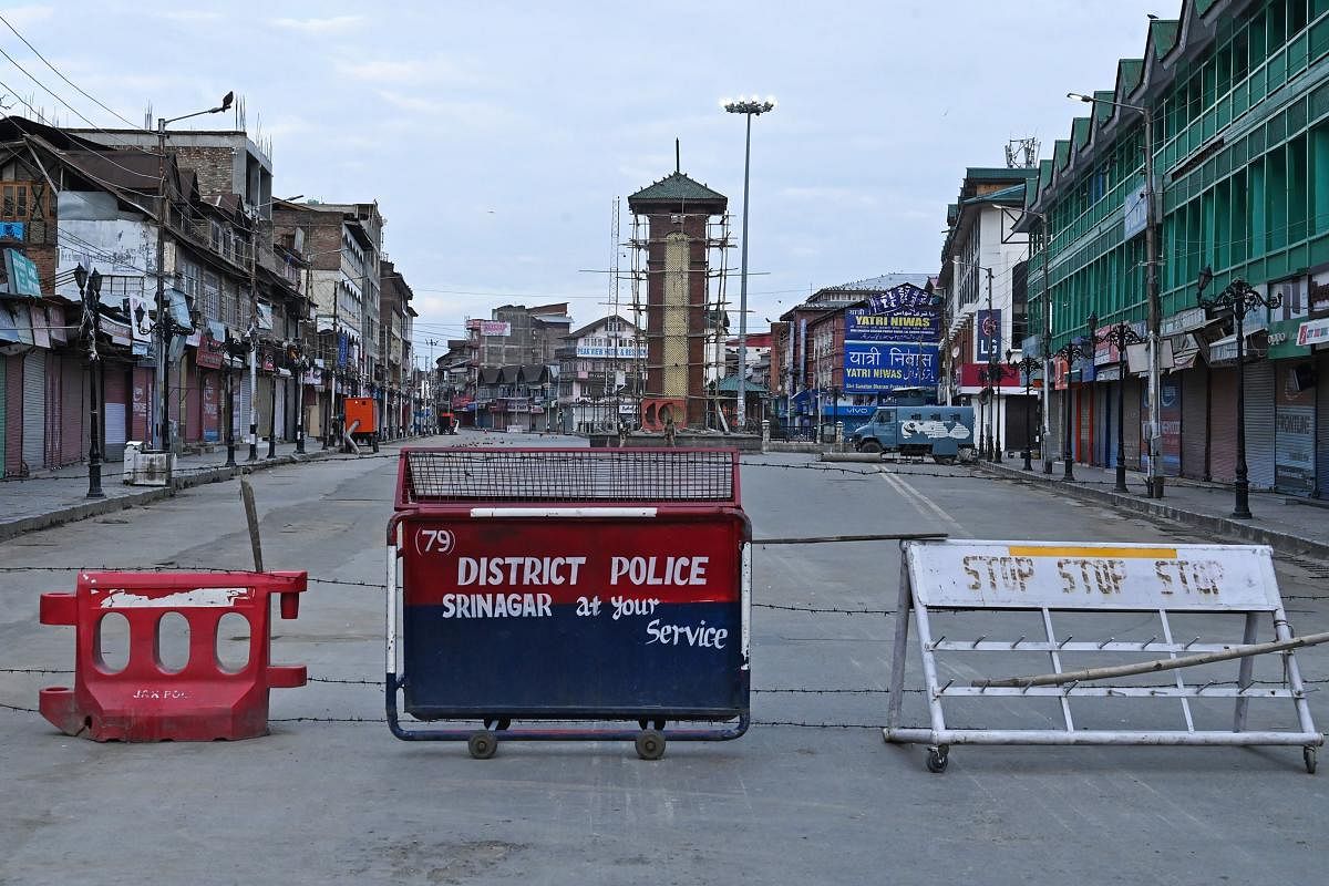 Security personnel (back) stand guard a street under the clock tower at Lalchowk during a lockdown in Srinagar. (AFP Photo)