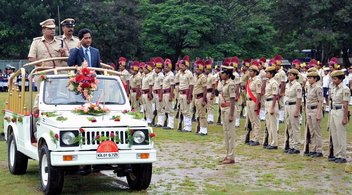 Deputy Commissioner Dr Bagadi Gautham receives a guard of honour at the Independence Day programme at the District Police Ground in Chikkamagaluru on Thursday. (Right) A woman ties Rakhi to a police officer at the programme.