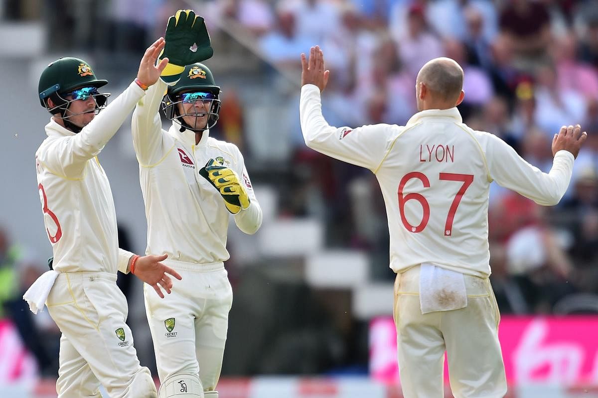 Australia's Nathan Lyon (R) and Australia's captain Tim Paine (C) celebrate the wicket of England's Stuart Broad for 11 runs on the second day of the second Ashes cricket Test match between England and Australia at Lord's Cricket Ground in London on Augus