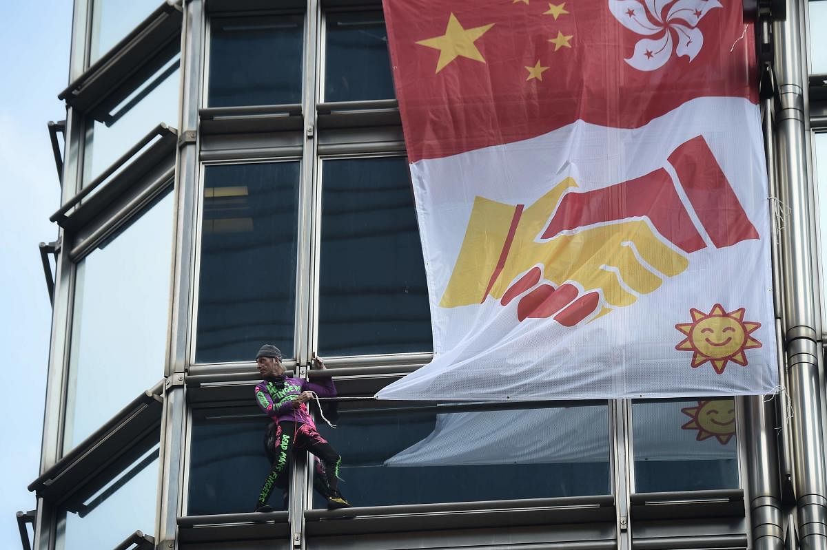 French urban climber Alain Robert, popularly known as the "French Spider-Man", secures a banner, showing shaking hands below a depiction of the Chinese and Hong Kong flags, during his ascent of the Cheung Kong Center building in Hong Kong. AFP