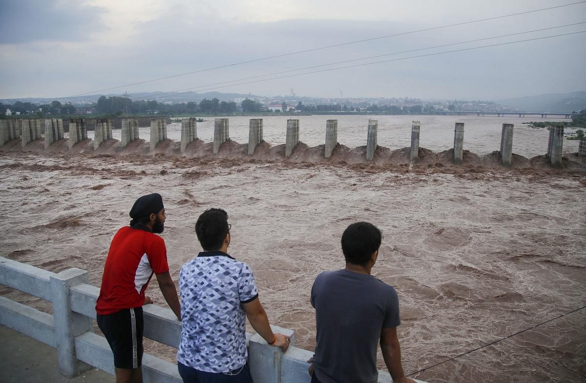 A group of people watch the swollen Tawi river following heavy rainfall, in Jammu, Wednesday, Aug 14, 2019. (PTI Photo for representation)