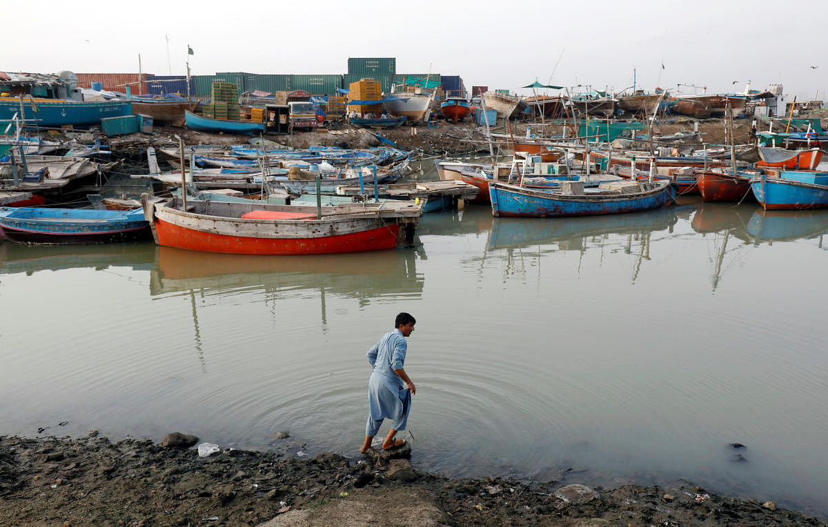 A man washes his feet in front of anchored fishing boats, near the port area in Karachi, Pakistan August 1, 2019. REUTERS/Akhtar Soomro