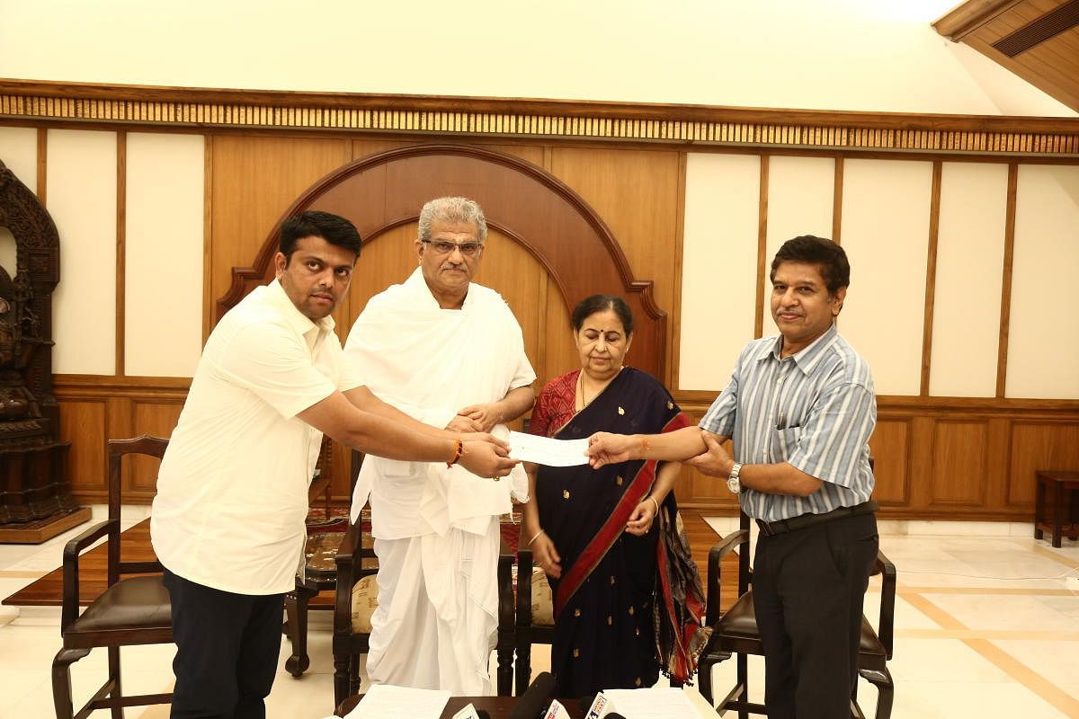 Belthangady MLA Harish Poonja receives cheque for Rs 50 lakh from SKDRDP Executive Director Dr L H Manjunath to take up relief works in the taluk. Dharmadhikari D Veerendra Heggade, and Hemavathi V Heggade looks on.