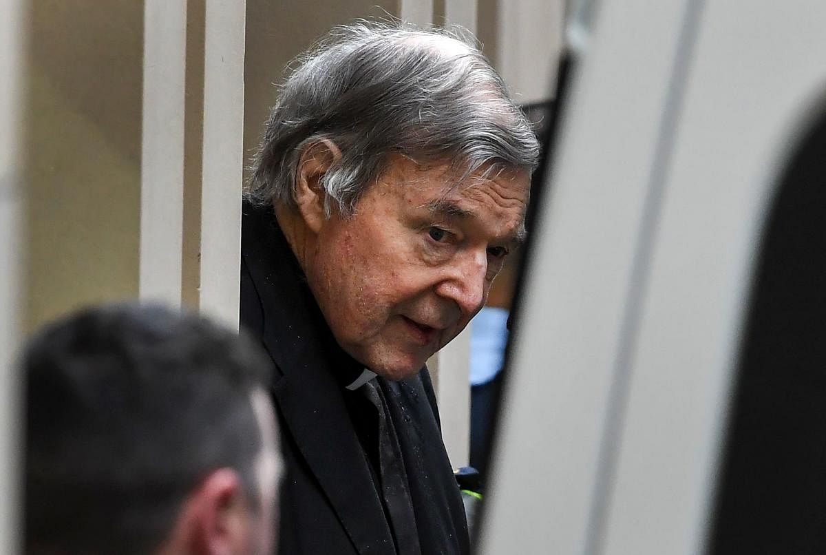 Cardinal George Pell (C) is escorted in handcuffs from the Supreme Court of Victoria in Melbourne. (AFP Photo)