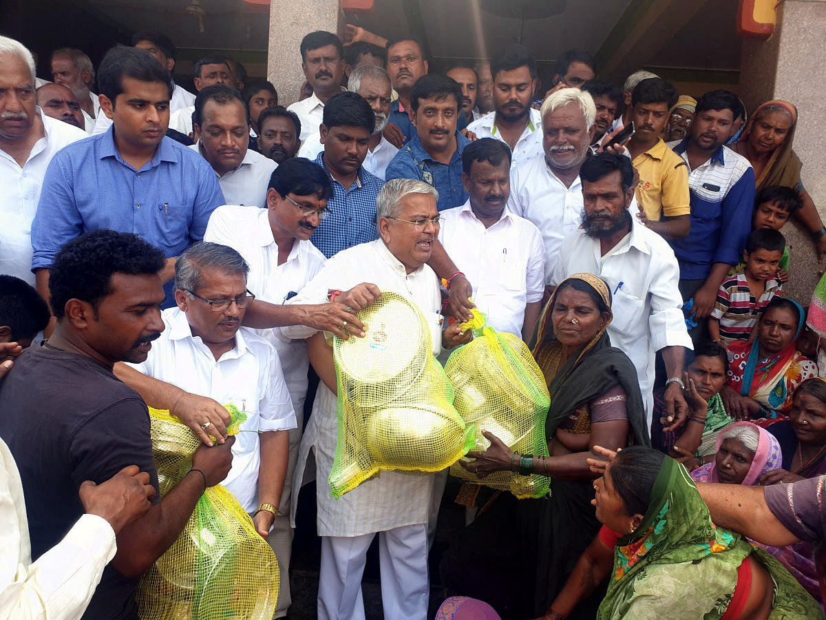 Chitradurga BJP MP A Narayanaswamy and Minister Govind Karjol distribute utensils at flood-hit at Roogi village in Mudhol taluk, Vijayapura district, on Thursday. DH Photo
