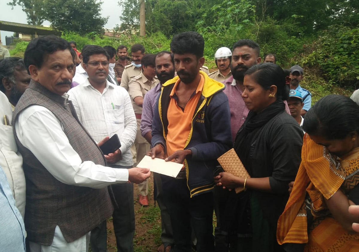 Virajpet legislator K G Bopaiah hands over a compensation cheque to the relatives of Leela, whose body was recovered in Thora on Thursday.