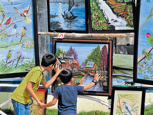 Two young visitors admire a painting on display at 'Chitra Santhe', a State-level exhibition-cum-sale of various handicrafts, organised by Karnataka Exhibition Authority at Dasara Exhibition Ground in Mysuru on Sunday. DH photo