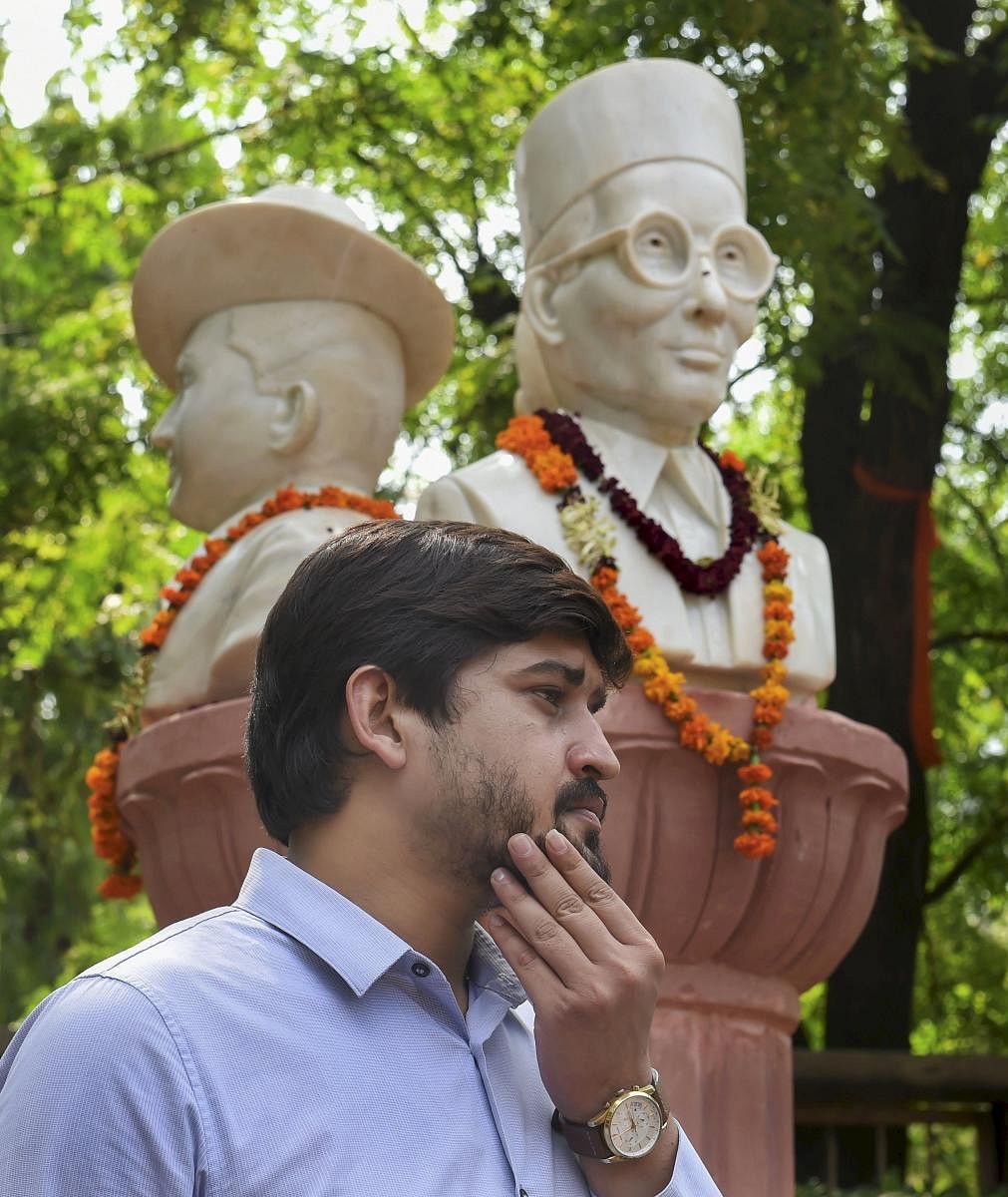 Delhi University Students' Union (DUSU) president Shakti Singh stands next to the busts of Veer Savarkar, Subhash Chandra Bose, and Bhagat Singh which were installed outside the Arts Faculty of the University, in New Delhi. (PTI Photo)