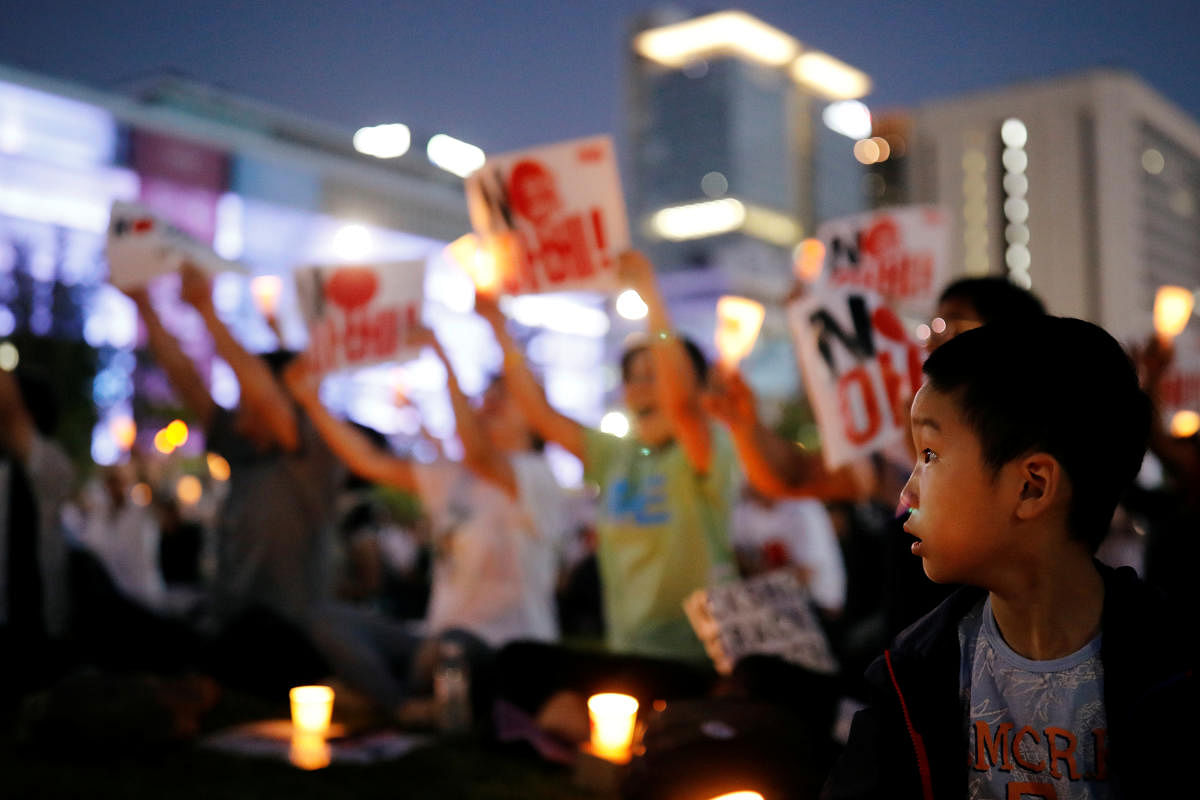 A boy looks on as South Korean people chant slogans during an anti-Japan rally in Seoul. Reuters