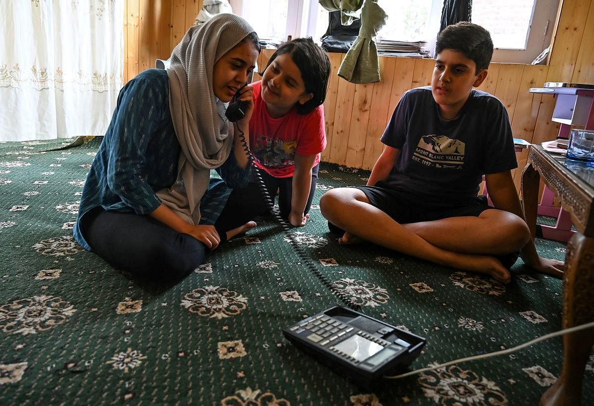 A Kashmiri Muslim family talks to relatives on a landline phone in Srinagar. AFP