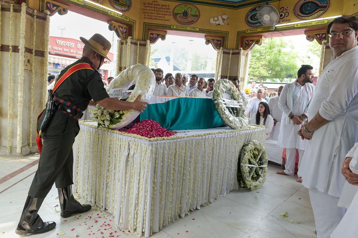 A soldier shifts Prime Minister Narendra Modi's wreath, which was laid by Union Defence Minister Rajnath Singh on the mortal remains of former finance minister Arun Jaitley before his last rites at Nigam Bodh Ghat. PTI photo