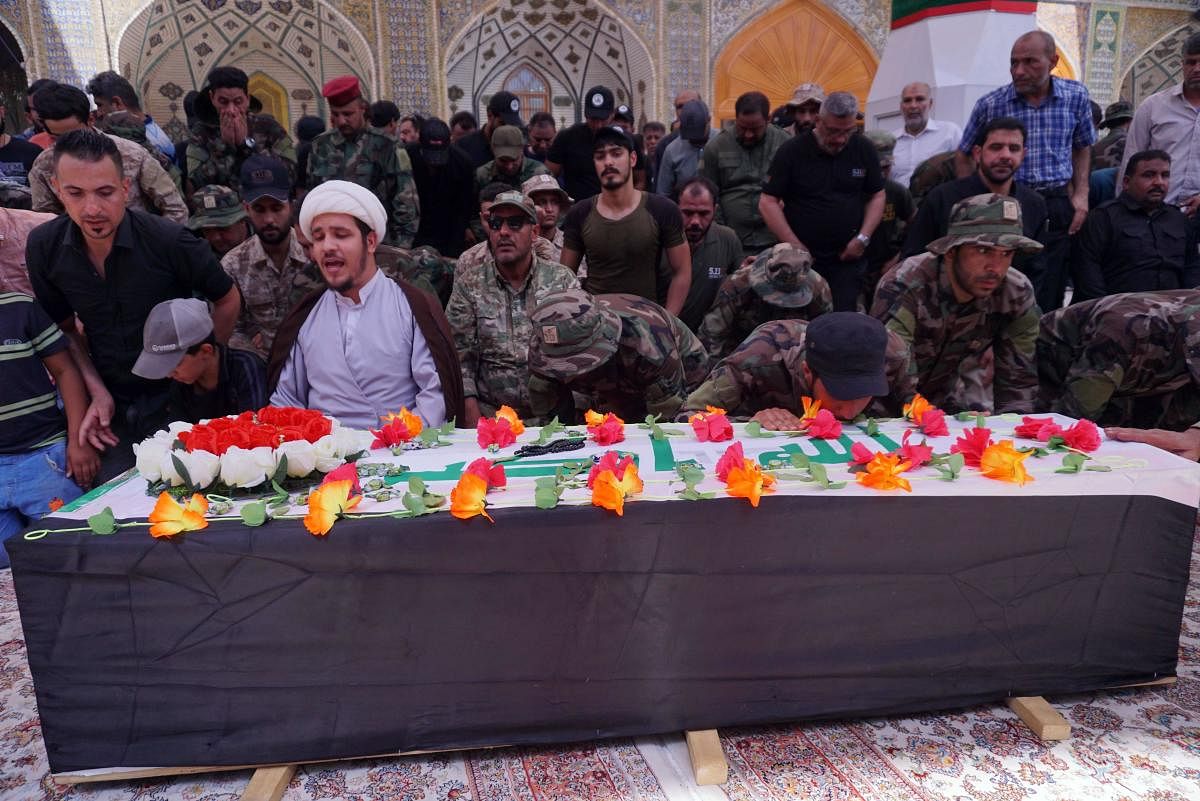 A Shiite Muslim cleric recites a prayer as members of Iraq's Hashed al-Shaabi (Popular Mobilisation units) paramilitary force surround the coffin of their comrade Kazem Mohsen, known by his nom de guerre Abu Ali al-Dabi. (AFP Photo)