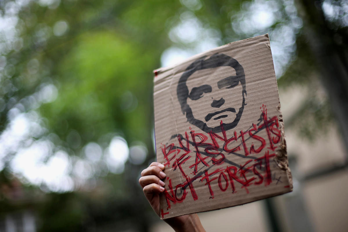 An activist holds a sign with an illustration of Brazilian President Jair Bolsonaro as they demand more Amazon rainforest protection at the embassy of Brazil in Mexico City, Mexico August 23, 2019. REUTERS/Edgard Garrido