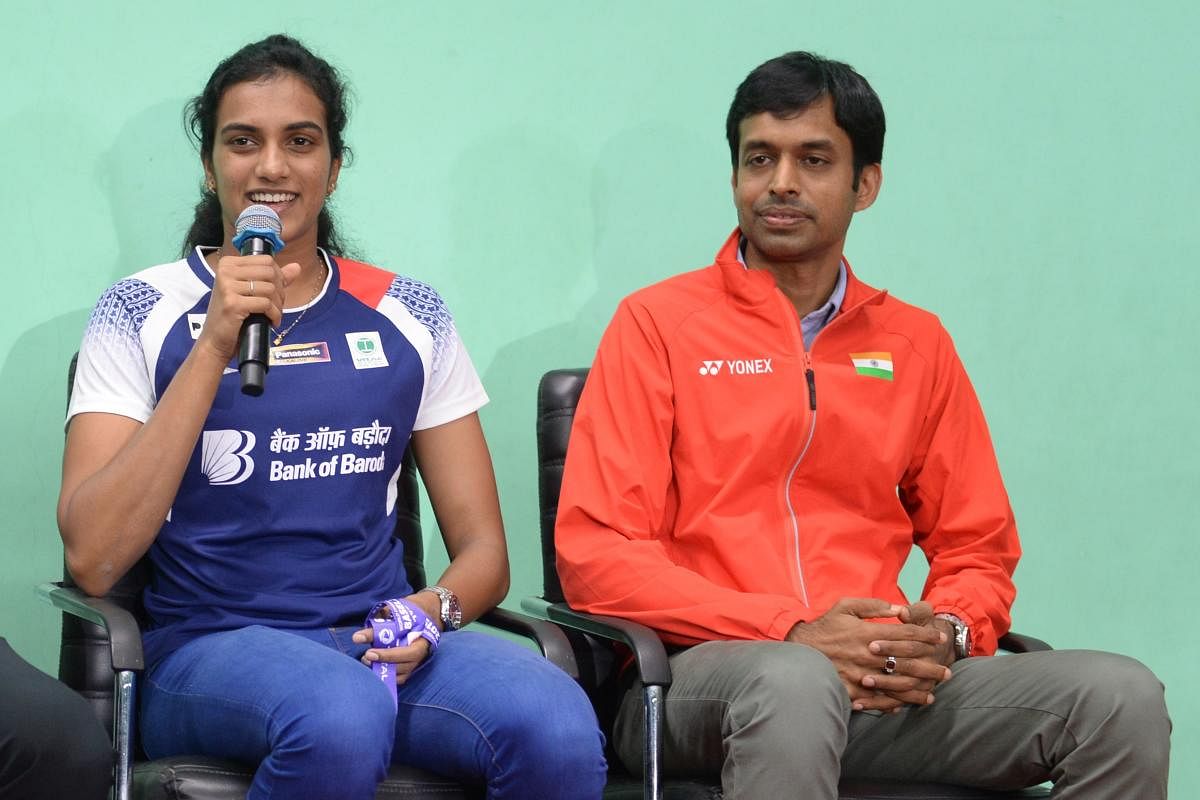 Indian badminton player Pusarla Venkata Sindhu (L) speaks next to her coach Pullela Gopichand at a press conference in Hyderabad on August 27, 2019. - Sindhu won a gold medal at the BWF Badminton World Championships in Basel. (Photo by NOAH SEELAM / AFP)