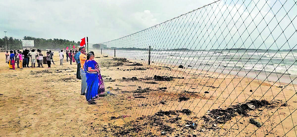 Visitors view the sea through the iron mesh at Malpe beach.