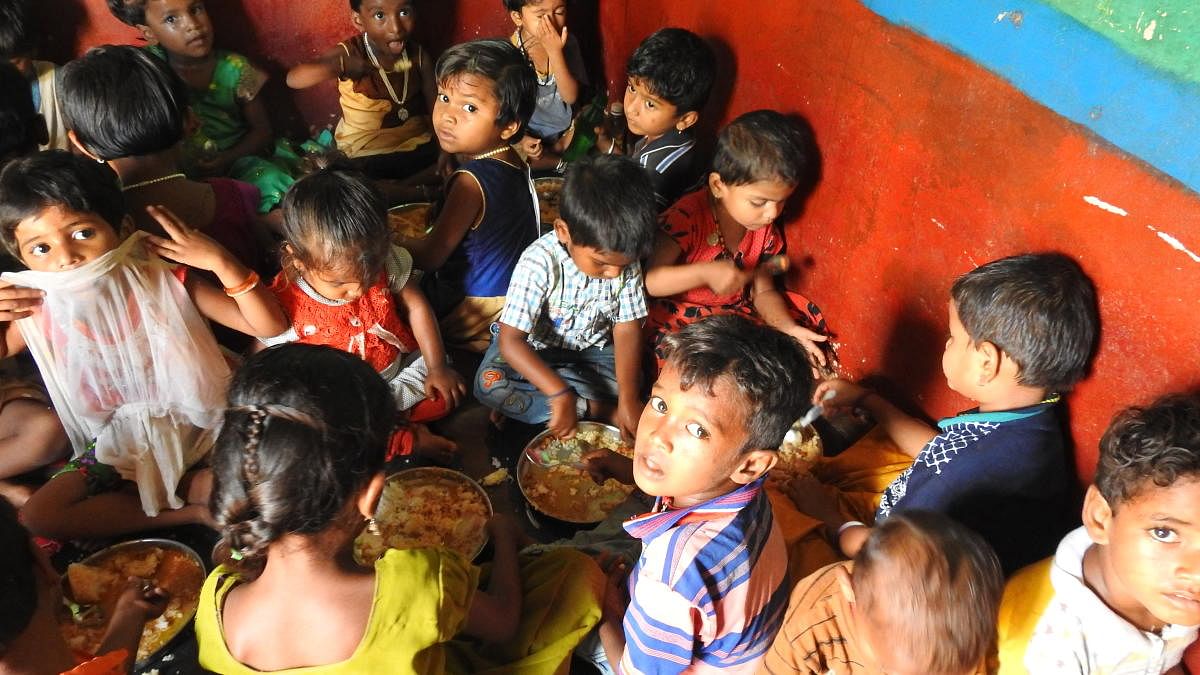 Two kids had to eat from the same plate at an Anganwadi due to the shortage of plates. (DH Photo/Anitha Pailoor)
